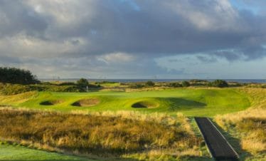 Dundonald Links 11th hole in Ayshire, Scotland. Golf green surrounded by 3 bunkers