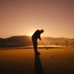 Golfer tees off at sunset