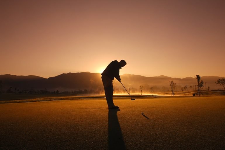 Golfer tees off at sunset